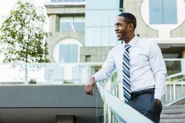 Handsome male african american business man CEO in a stylish corporate elegant suit in a business center outdoors - Black male commuter going to work, city and financial district in the background