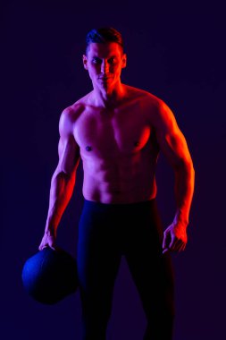 Stüdyoda kaslı vücut eğitimi almış atletik bir adam aktif bir adam spor yapıyor, renkli ışıklandırma ve arka plan, fitness, spor ve sağlık yaşam tarzı konseptleri