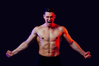 Stüdyoda kaslı vücut eğitimi almış atletik bir adam aktif bir adam spor yapıyor, renkli ışıklandırma ve arka plan, fitness, spor ve sağlık yaşam tarzı konseptleri