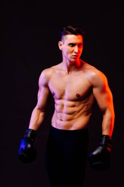 Stüdyoda kaslı vücut eğitimi almış atletik bir adam aktif bir adam spor yapıyor, renkli ışıklandırma ve arka plan, fitness, spor ve sağlık yaşam tarzı konseptleri