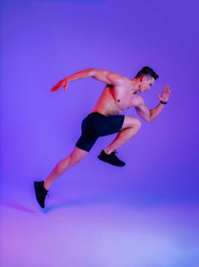 Stüdyoda kaslı vücut eğitimi almış atletik bir adam aktif bir adam spor yapıyor, renkli ışıklandırma ve arka plan, fitness, spor ve sağlık yaşam tarzı konseptleri