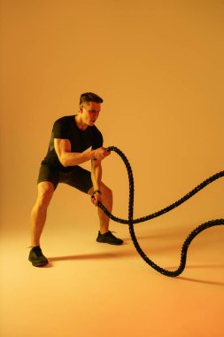 Stüdyoda kaslı vücut eğitimi almış atletik bir adam aktif bir adam spor yapıyor, renkli ışıklandırma ve arka plan, fitness, spor ve sağlık yaşam tarzı konseptleri