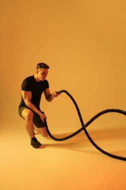 Stüdyoda kaslı vücut eğitimi almış atletik bir adam aktif bir adam spor yapıyor, renkli ışıklandırma ve arka plan, fitness, spor ve sağlık yaşam tarzı konseptleri