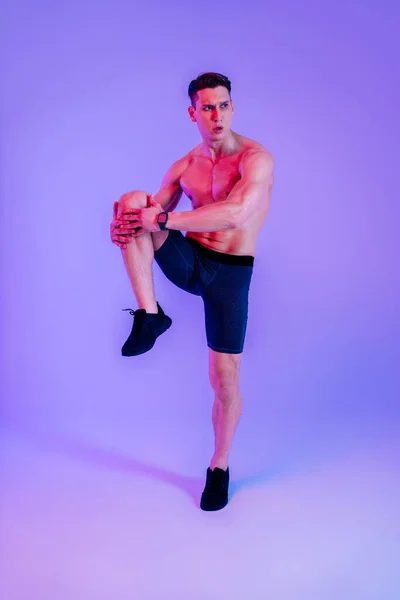 スタジオでの筋肉のトレーニングに適したアスレチックマン ワークアウト カラフルな照明と背景 フィットネス スポーツ 健康ライフスタイルに関する概念を行うアクティブな男 — ストック写真