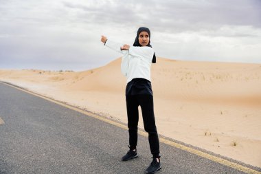 Ortadoğulu güzel bir Arap kadın çölde tesettür eğitimi alıyor sportif atletik müslüman kadın, burkini spor kıyafetleri giyiyor spor yapıyor.