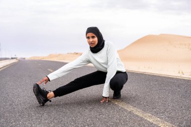 Ortadoğulu güzel bir Arap kadın çölde tesettür eğitimi alıyor sportif atletik müslüman kadın, burkini spor kıyafetleri giyiyor spor yapıyor.