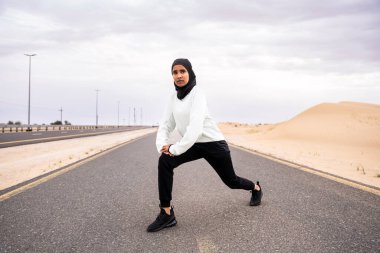 Ortadoğulu güzel bir Arap kadın çölde tesettür eğitimi alıyor sportif atletik müslüman kadın, burkini spor kıyafetleri giyiyor spor yapıyor.