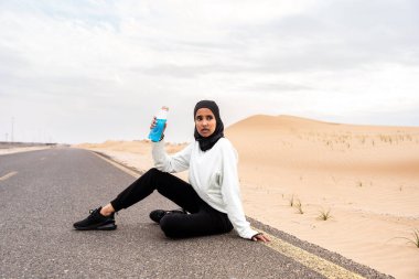 Ortadoğulu güzel bir Arap kadın çölde tesettür eğitimi alıyor sportif atletik müslüman kadın, burkini spor kıyafetleri giyiyor spor yapıyor.