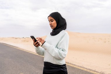 Ortadoğulu güzel bir Arap kadın çölde tesettür eğitimi alıyor sportif atletik müslüman kadın, burkini spor kıyafetleri giyiyor spor yapıyor.