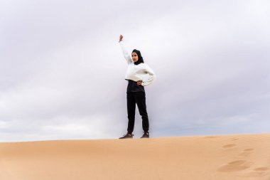 Ortadoğulu güzel bir Arap kadın çölde tesettür eğitimi alıyor sportif atletik müslüman kadın, burkini spor kıyafetleri giyiyor spor yapıyor.