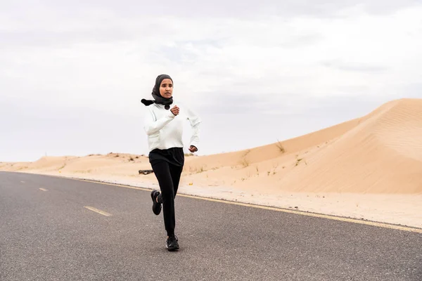 在沙漠地区 漂亮的中东阿拉伯女人穿着头巾训练 穿着伯基尼运动服的有运动肌肉的成年女性正在做健身锻炼 — 图库照片