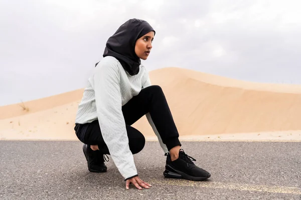 stock image Beautiful middle-eastern arab woman wearing hijab training outdoors in a desert area - Sportive athletic muslim adult female wearing burkini sportswear doing fitness workout