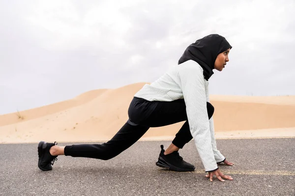 在沙漠地区 漂亮的中东阿拉伯女人穿着头巾训练 穿着伯基尼运动服的有运动肌肉的成年女性正在做健身锻炼 — 图库照片