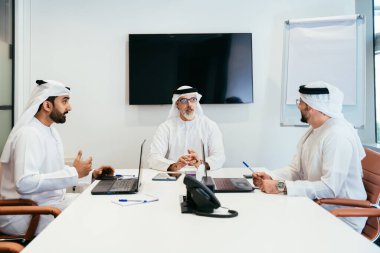 Dubai 'deki ofiste geleneksel emirati kıyafetleri giyen bir grup orta doğulu iş adamı BAE' de çalışıyor ve beyin fırtınası yapıyor.