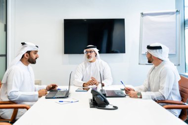 Dubai 'deki ofiste geleneksel emirati kıyafetleri giyen bir grup orta doğulu iş adamı BAE' de çalışıyor ve beyin fırtınası yapıyor.