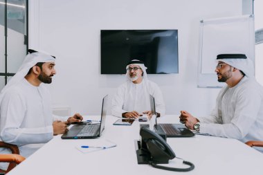 Dubai 'deki ofiste geleneksel emirati kıyafetleri giyen bir grup orta doğulu iş adamı BAE' de çalışıyor ve beyin fırtınası yapıyor.