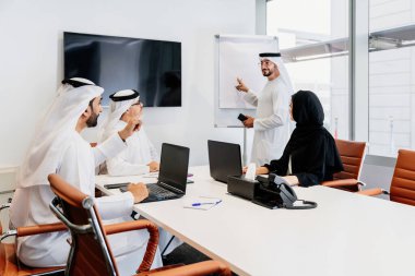 Dubai 'deki ofiste geleneksel emirati kıyafetleri giyen bir grup orta doğulu iş adamı BAE' de çalışıyor ve beyin fırtınası yapıyor.