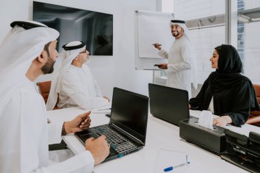 Dubai 'deki ofiste geleneksel emirati kıyafetleri giyen bir grup orta doğulu iş adamı BAE' de çalışıyor ve beyin fırtınası yapıyor.
