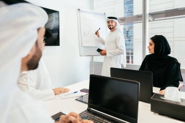 Dubai 'deki ofiste geleneksel emirati kıyafetleri giyen bir grup orta doğulu iş adamı BAE' de çalışıyor ve beyin fırtınası yapıyor.