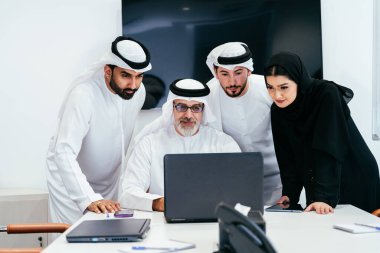 Dubai 'deki ofiste geleneksel emirati kıyafetleri giyen bir grup orta doğulu iş adamı BAE' de çalışıyor ve beyin fırtınası yapıyor.