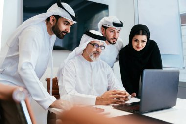 Dubai 'deki ofiste geleneksel emirati kıyafetleri giyen bir grup orta doğulu iş adamı BAE' de çalışıyor ve beyin fırtınası yapıyor.