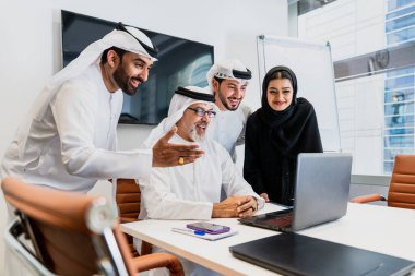 Dubai 'deki ofiste geleneksel emirati kıyafetleri giyen bir grup orta doğulu iş adamı BAE' de çalışıyor ve beyin fırtınası yapıyor.