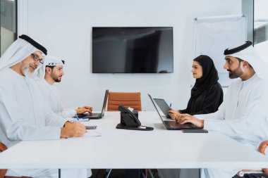 Dubai 'deki ofiste geleneksel emirati kıyafetleri giyen bir grup orta doğulu iş adamı BAE' de çalışıyor ve beyin fırtınası yapıyor.