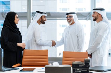 Dubai 'deki ofiste geleneksel emirati kıyafetleri giyen bir grup orta doğulu iş adamı BAE' de çalışıyor ve beyin fırtınası yapıyor.