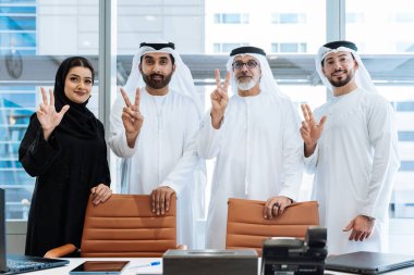 Dubai 'deki ofiste geleneksel emirati kıyafetleri giyen bir grup orta doğulu iş adamı BAE' de çalışıyor ve beyin fırtınası yapıyor.
