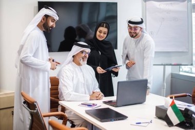 Dubai 'deki ofiste geleneksel emirati kıyafetleri giyen bir grup orta doğulu iş adamı BAE' de çalışıyor ve beyin fırtınası yapıyor.