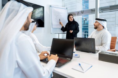 Dubai 'deki ofiste geleneksel emirati kıyafetleri giyen bir grup orta doğulu iş adamı BAE' de çalışıyor ve beyin fırtınası yapıyor.