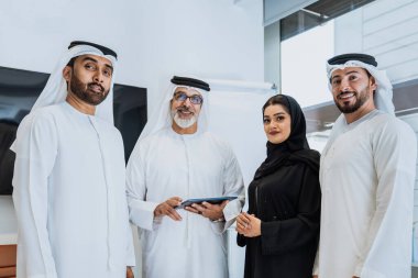 Dubai 'deki ofiste geleneksel emirati kıyafetleri giyen bir grup orta doğulu iş adamı BAE' de çalışıyor ve beyin fırtınası yapıyor.