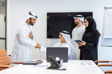 Dubai 'deki ofiste geleneksel emirati kıyafetleri giyen bir grup orta doğulu iş adamı BAE' de çalışıyor ve beyin fırtınası yapıyor.