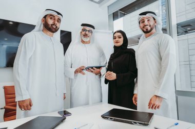 Dubai 'deki ofiste geleneksel emirati kıyafetleri giyen bir grup orta doğulu iş adamı BAE' de çalışıyor ve beyin fırtınası yapıyor.