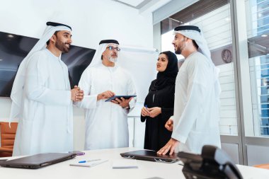 Dubai 'deki ofiste geleneksel emirati kıyafetleri giyen bir grup orta doğulu iş adamı BAE' de çalışıyor ve beyin fırtınası yapıyor.