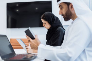 Dubai 'deki ofiste geleneksel emirati kıyafetleri giyen bir grup orta doğulu iş adamı BAE' de çalışıyor ve beyin fırtınası yapıyor.