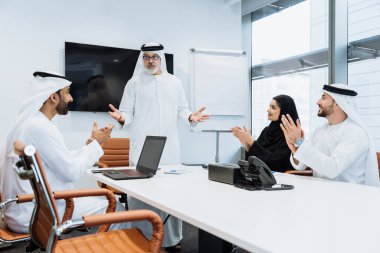 Dubai 'deki ofiste geleneksel emirati kıyafetleri giyen bir grup orta doğulu iş adamı BAE' de çalışıyor ve beyin fırtınası yapıyor.