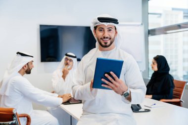 Dubai 'deki ofiste geleneksel emirati kıyafetleri giyen bir grup orta doğulu iş adamı BAE' de çalışıyor ve beyin fırtınası yapıyor.