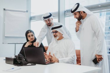 Dubai 'deki ofiste geleneksel emirati kıyafetleri giyen bir grup orta doğulu iş adamı BAE' de çalışıyor ve beyin fırtınası yapıyor.