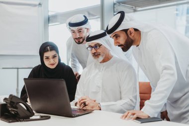 Dubai 'deki ofiste geleneksel emirati kıyafetleri giyen bir grup orta doğulu iş adamı BAE' de çalışıyor ve beyin fırtınası yapıyor.