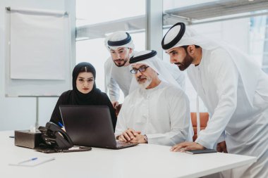 Dubai 'deki ofiste geleneksel emirati kıyafetleri giyen bir grup orta doğulu iş adamı BAE' de çalışıyor ve beyin fırtınası yapıyor.