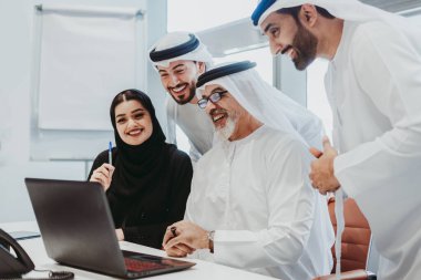 Dubai 'deki ofiste geleneksel emirati kıyafetleri giyen bir grup orta doğulu iş adamı BAE' de çalışıyor ve beyin fırtınası yapıyor.