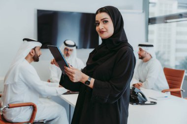 Dubai 'deki ofiste geleneksel emirati kıyafetleri giyen bir grup orta doğulu iş adamı BAE' de çalışıyor ve beyin fırtınası yapıyor.