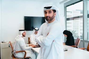 Dubai 'deki ofiste geleneksel emirati kıyafetleri giyen bir grup orta doğulu iş adamı BAE' de çalışıyor ve beyin fırtınası yapıyor.