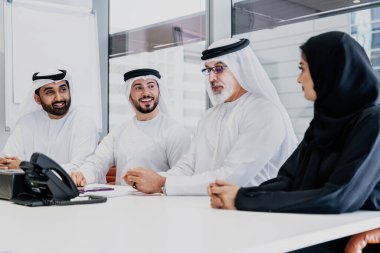 Dubai 'deki ofiste geleneksel emirati kıyafetleri giyen bir grup orta doğulu iş adamı BAE' de çalışıyor ve beyin fırtınası yapıyor.