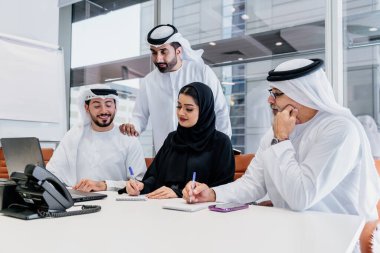 Dubai 'deki ofiste geleneksel emirati kıyafetleri giyen bir grup orta doğulu iş adamı BAE' de çalışıyor ve beyin fırtınası yapıyor.