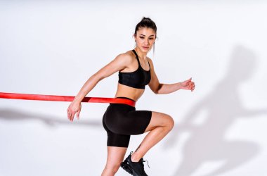 Spor aletlerini kullanarak spor salonunda antrenman yapan genç bir bayan sporcu. Formda kadın vücut çalışıyor. Zindelik, sağlık ve spor hazırlığı kavramları.