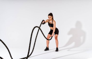 Spor aletlerini kullanarak spor salonunda antrenman yapan genç bir bayan sporcu. Formda kadın vücut çalışıyor. Zindelik, sağlık ve spor hazırlığı kavramları.