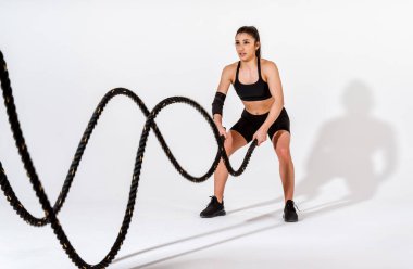 Spor aletlerini kullanarak spor salonunda antrenman yapan genç bir bayan sporcu. Formda kadın vücut çalışıyor. Zindelik, sağlık ve spor hazırlığı kavramları.