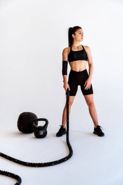 Spor aletlerini kullanarak spor salonunda antrenman yapan genç bir bayan sporcu. Formda kadın vücut çalışıyor. Zindelik, sağlık ve spor hazırlığı kavramları.